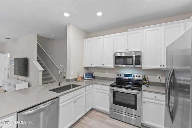 kitchen featuring white cabinets, kitchen peninsula, sink, and appliances with stainless steel finishes