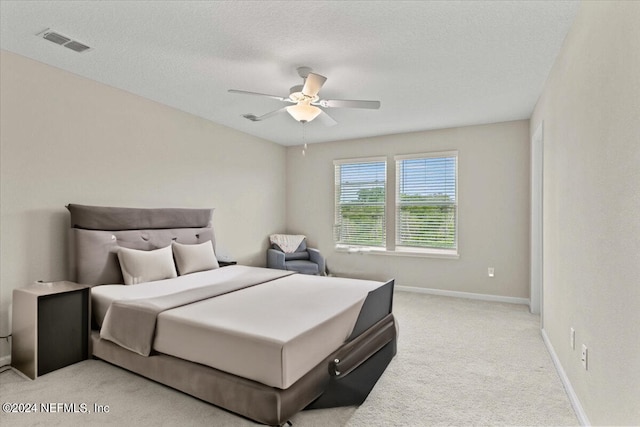 carpeted bedroom with ceiling fan and a textured ceiling