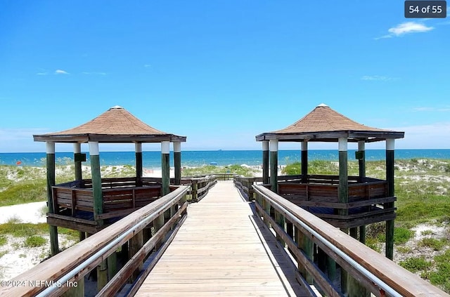 view of dock with a gazebo, a water view, and a view of the beach