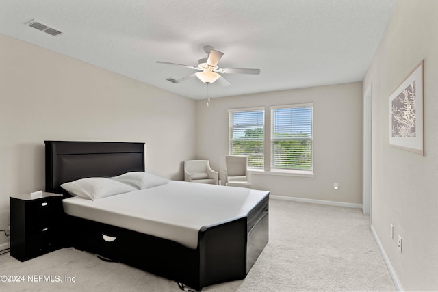 bedroom with a textured ceiling, light colored carpet, and ceiling fan