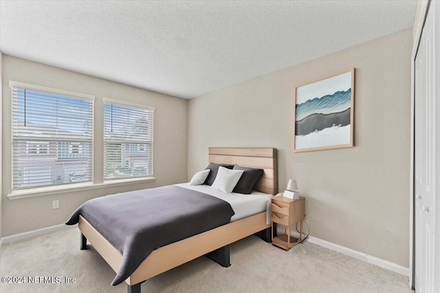 bedroom featuring a textured ceiling, light colored carpet, and a closet