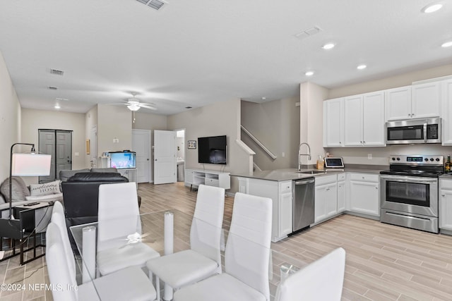 kitchen featuring white cabinets, ceiling fan, appliances with stainless steel finishes, and light hardwood / wood-style flooring