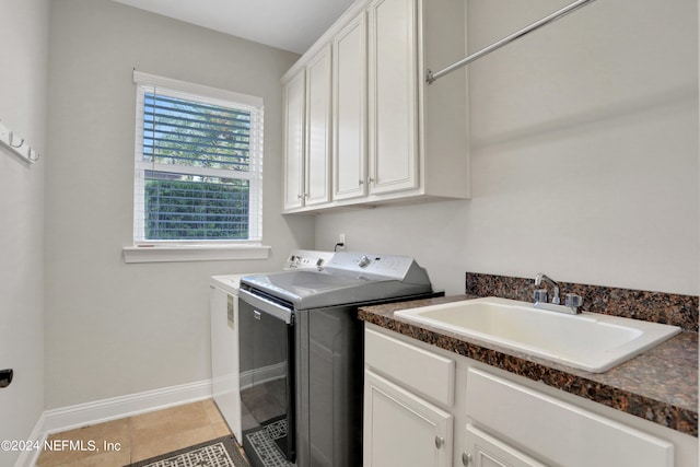 clothes washing area with baseboards, a sink, washer and dryer, light tile patterned floors, and cabinet space