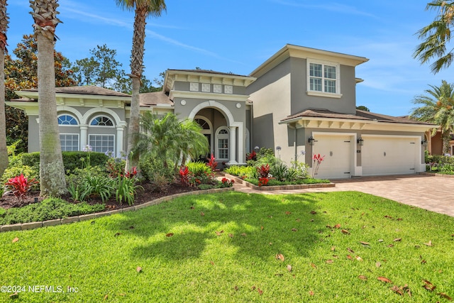 mediterranean / spanish-style house with stucco siding, decorative driveway, and a front yard