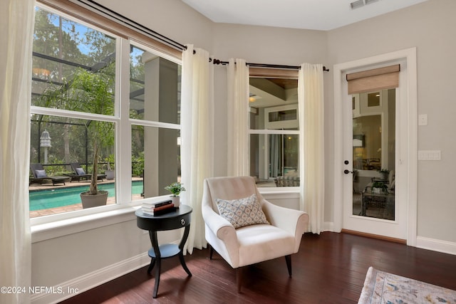 living area with baseboards, dark wood-style floors, visible vents, and plenty of natural light