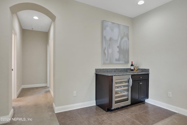 bar with a dry bar, beverage cooler, baseboards, recessed lighting, and arched walkways