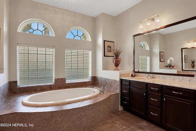 full bath with plenty of natural light, vanity, a garden tub, and tile patterned flooring