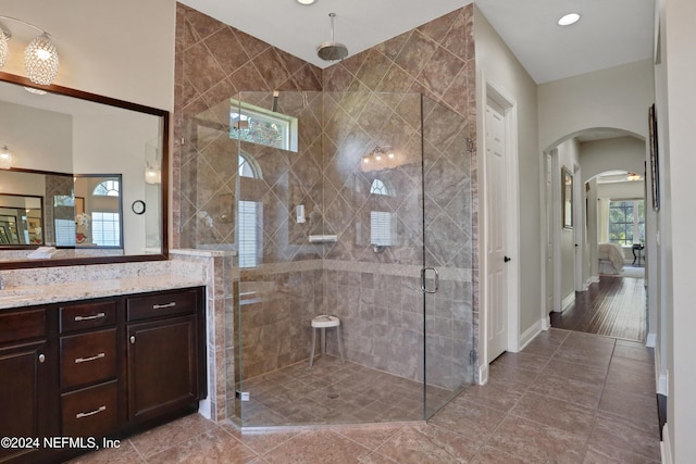 full bath featuring a shower stall, baseboards, vanity, and ensuite bath