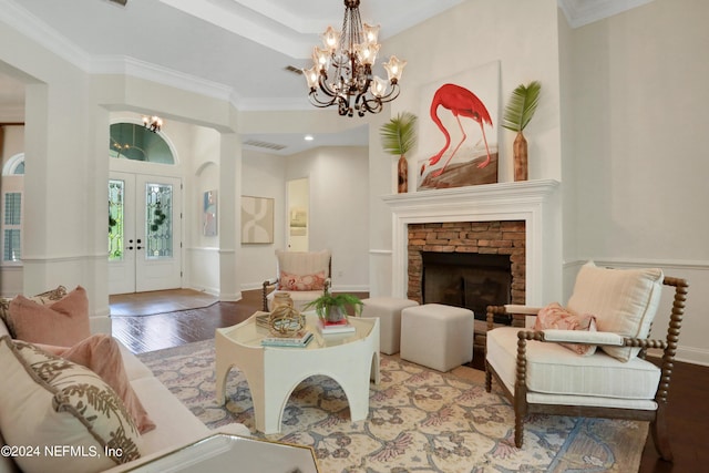 living room with a stone fireplace, an inviting chandelier, french doors, and wood finished floors