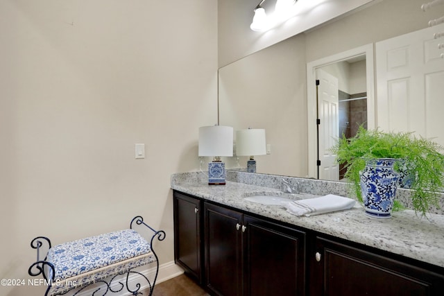 full bathroom with baseboards, vanity, and walk in shower