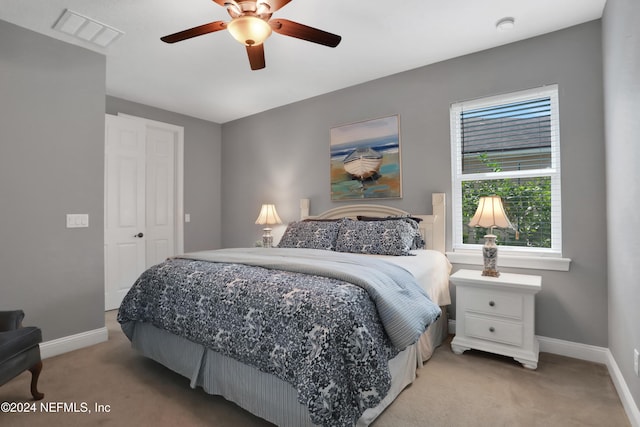 bedroom with light colored carpet, ceiling fan, visible vents, and baseboards