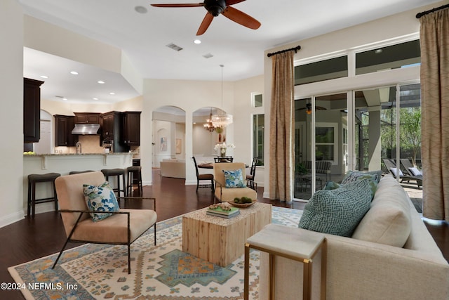 living room with ceiling fan with notable chandelier, recessed lighting, dark wood finished floors, and visible vents