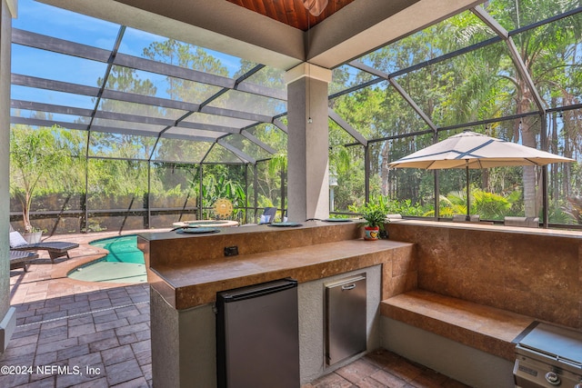 view of patio / terrace featuring a lanai, an outdoor pool, and exterior kitchen