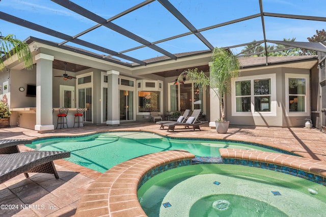 view of swimming pool featuring ceiling fan, a patio area, exterior bar, and a lanai