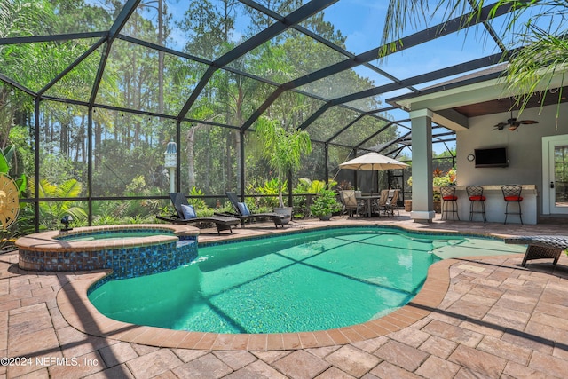 view of swimming pool with a lanai, a pool with connected hot tub, ceiling fan, and a patio area