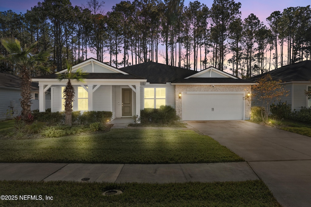 single story home featuring a lawn and a garage