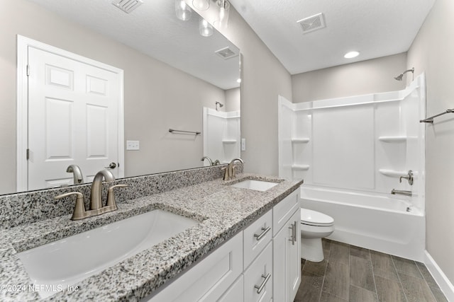 full bathroom with dual sinks, wood-type flooring, large vanity, toilet, and bathing tub / shower combination