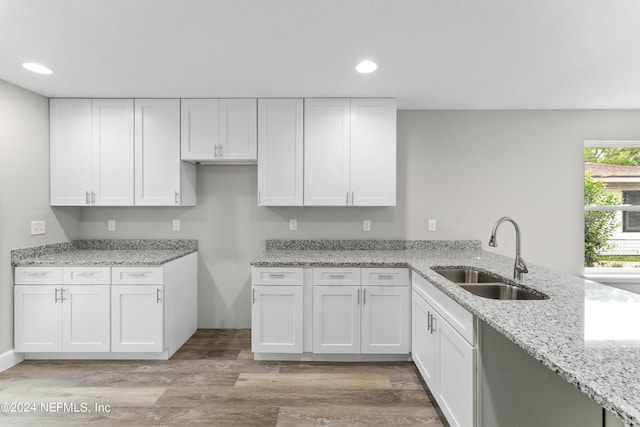 kitchen featuring white cabinets, sink, light stone countertops, and light wood-type flooring