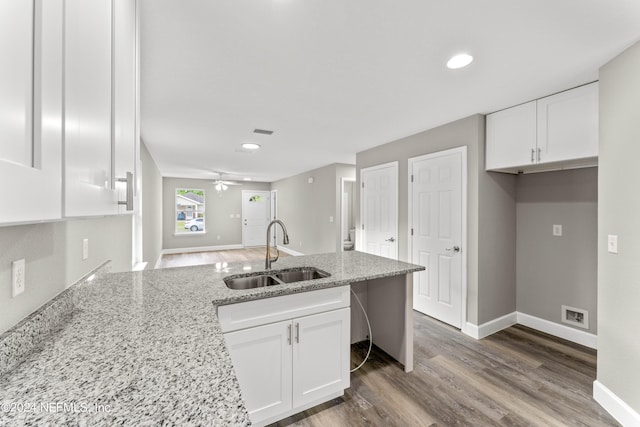 kitchen with light stone countertops, ceiling fan, wood-type flooring, sink, and white cabinets