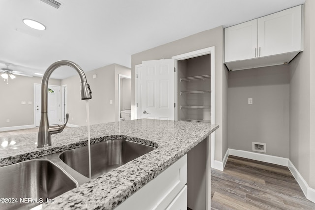 kitchen with light stone counters, sink, light hardwood / wood-style floors, and white cabinets