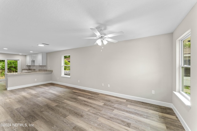 unfurnished living room with ceiling fan, hardwood / wood-style floors, and sink