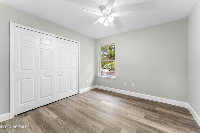 unfurnished bedroom with ceiling fan, a closet, a textured ceiling, and wood-type flooring