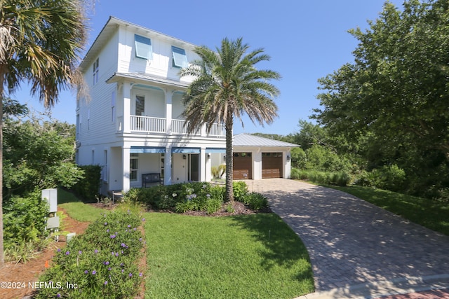 view of front of property with a front yard, a garage, a balcony, and covered porch