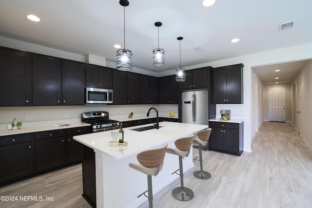 kitchen featuring pendant lighting, sink, a breakfast bar, stainless steel appliances, and a center island with sink