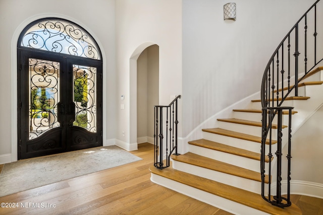 5275 Bentpine Cove Rd, Jacksonville, FL 32224 - foyer entrance featuring french doors, arched walkways, wood finished floors, stairs, and a towering ceiling