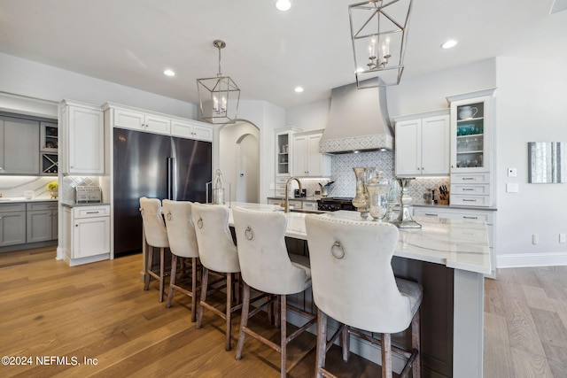 5275 Bentpine Cove Rd, Jacksonville, FL 32224 - kitchen featuring custom exhaust hood, stainless steel fridge, tasteful backsplash, light wood-type flooring, and a large island with sink