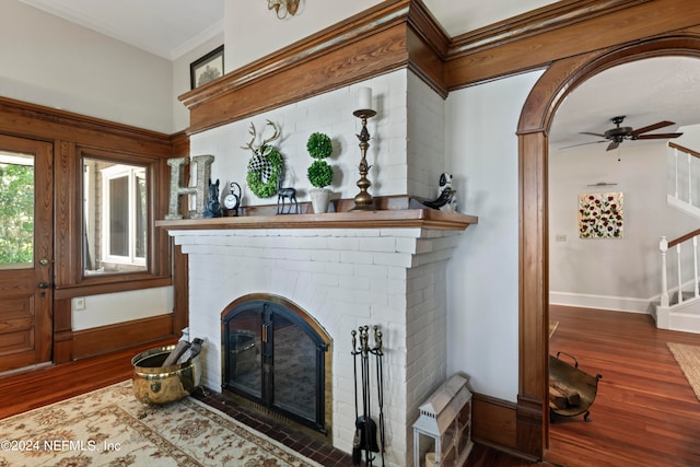 room details featuring ceiling fan, hardwood / wood-style flooring, ornamental molding, and a brick fireplace