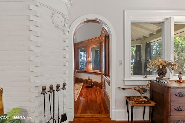 hall with brick wall and hardwood / wood-style flooring