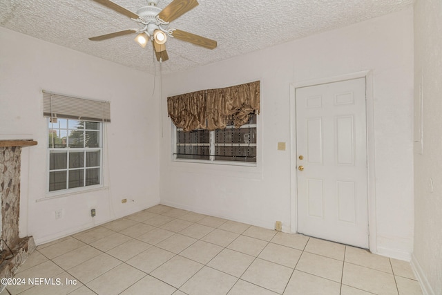 tiled empty room featuring ceiling fan and a textured ceiling