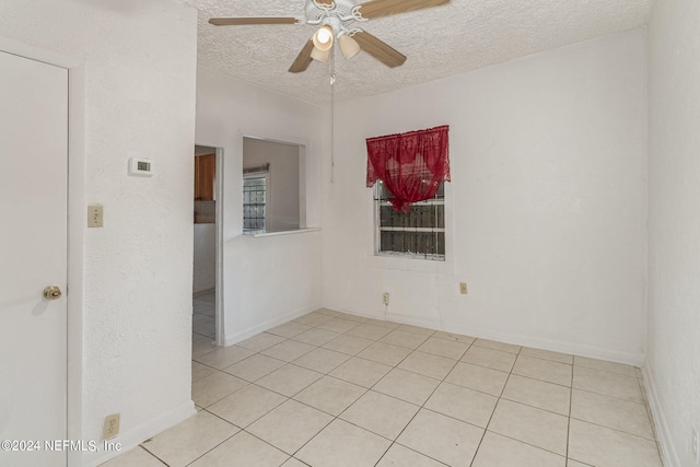 spare room with a textured ceiling, ceiling fan, and light tile floors