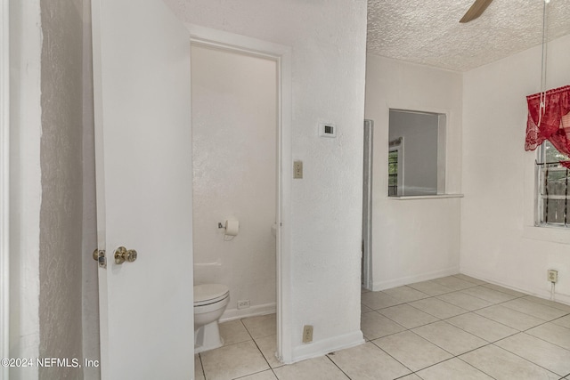 bathroom featuring ceiling fan, tile flooring, a textured ceiling, and toilet