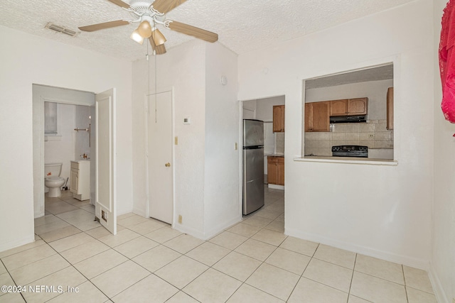 kitchen featuring backsplash, stove, ceiling fan, stainless steel fridge, and light tile floors