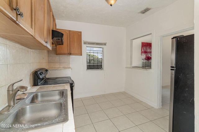 kitchen with a textured ceiling, stainless steel fridge, exhaust hood, backsplash, and sink