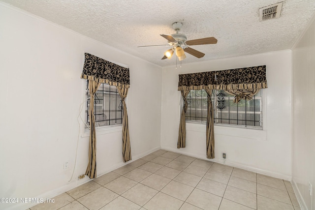 tiled empty room with a textured ceiling, ornamental molding, and ceiling fan