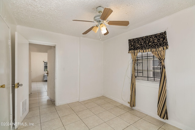 unfurnished room with a textured ceiling, ceiling fan, and light tile floors