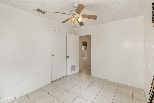 unfurnished bedroom with a textured ceiling, ceiling fan, light tile floors, and crown molding