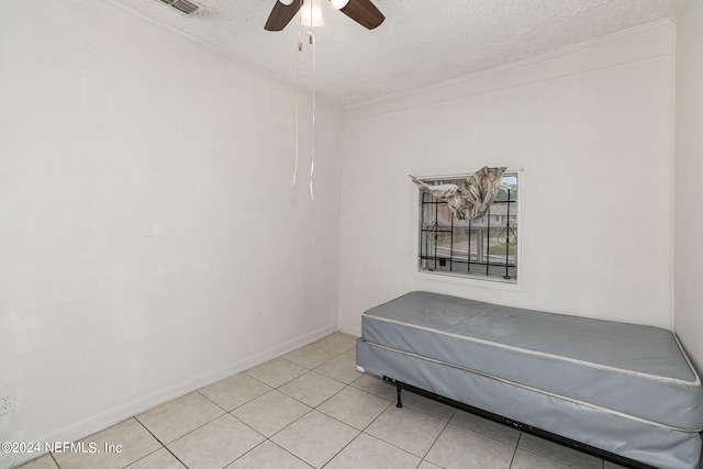 bedroom featuring a textured ceiling, ceiling fan, and light tile floors