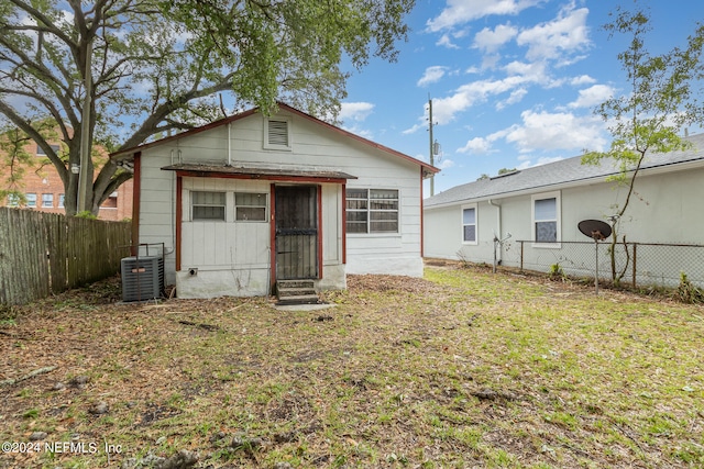 rear view of property featuring central air condition unit and a yard