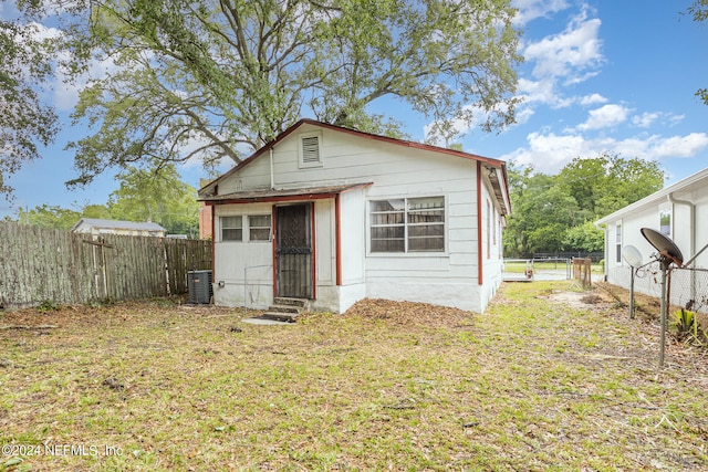 exterior space featuring central AC unit and a front lawn