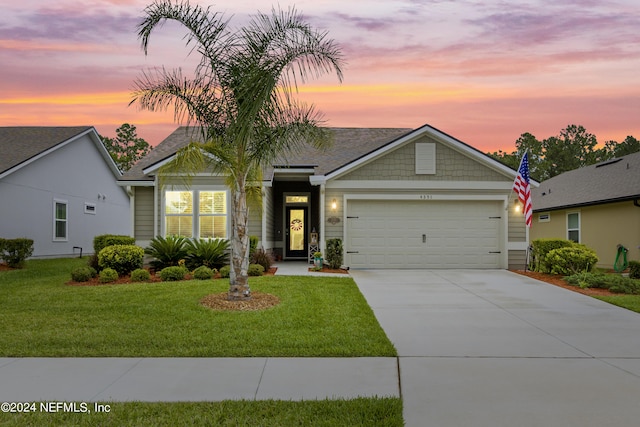 view of front of property with a garage and a lawn