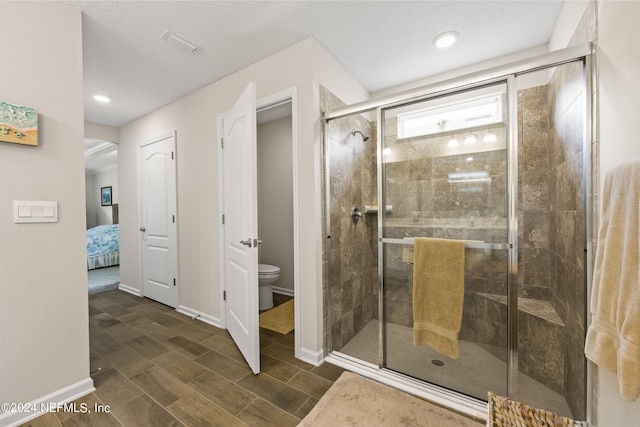 bathroom featuring a shower with shower door and toilet