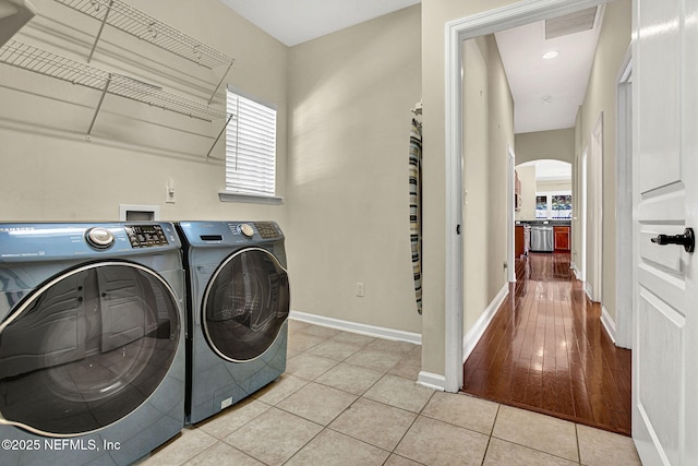 laundry area with washing machine and dryer and light tile patterned floors