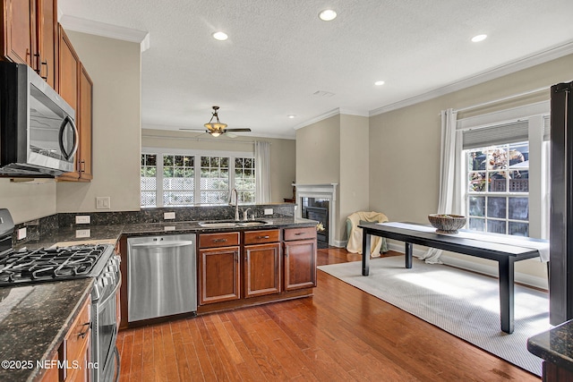 kitchen with stainless steel appliances, sink, ornamental molding, a textured ceiling, and hardwood / wood-style floors