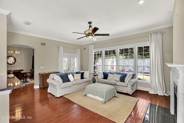 living room with ornamental molding, dark wood-type flooring, and ceiling fan with notable chandelier