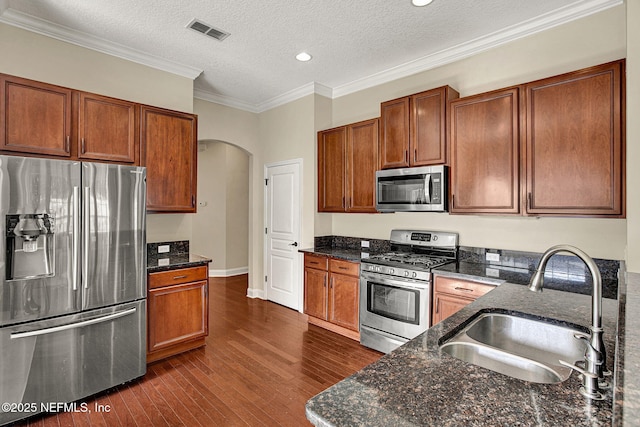 kitchen featuring appliances with stainless steel finishes, sink, dark stone counters, and dark hardwood / wood-style floors