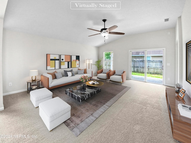 carpeted living room with ceiling fan and vaulted ceiling